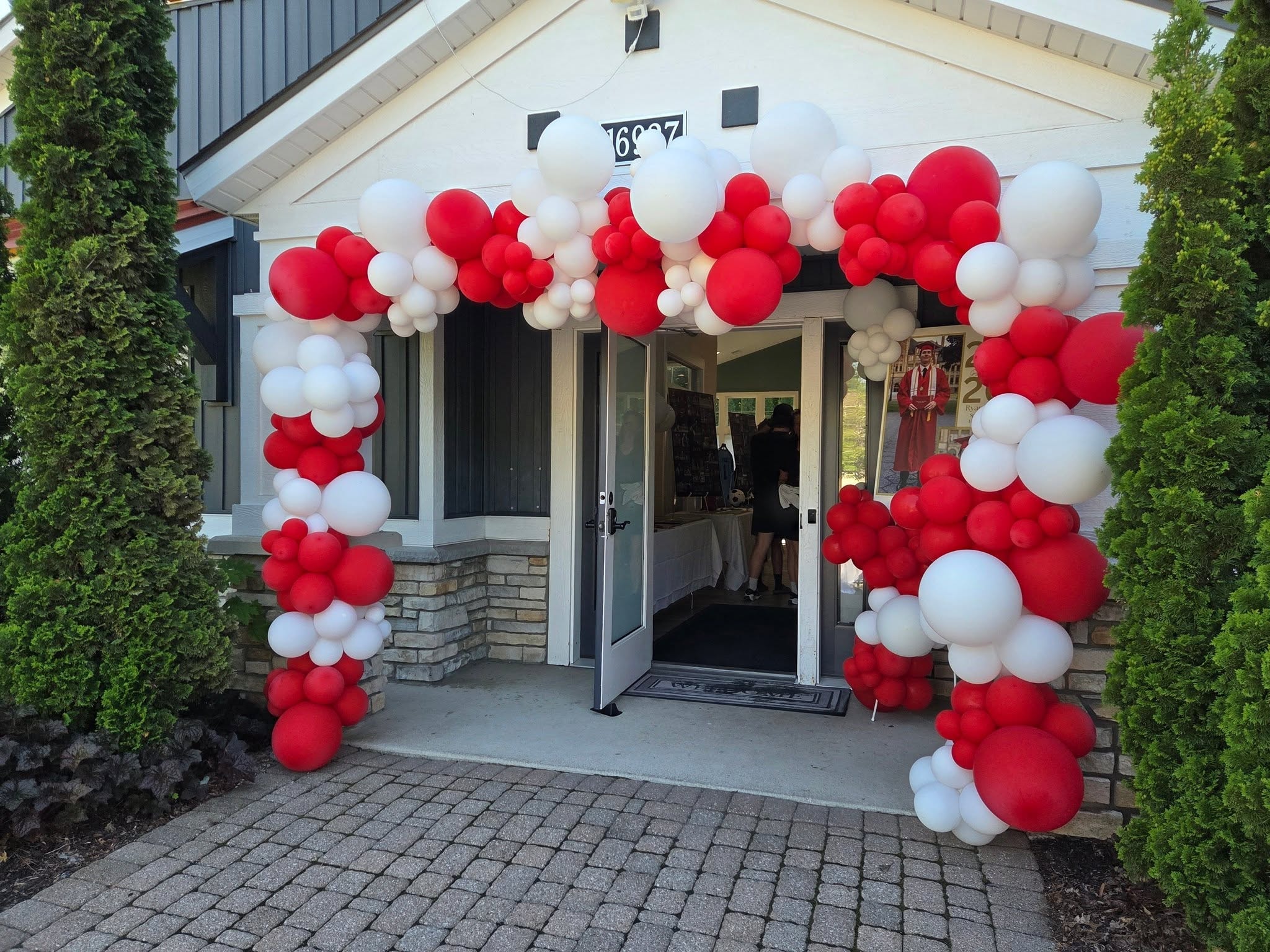 Red and white outdoor graduation balloon arch over home entrance