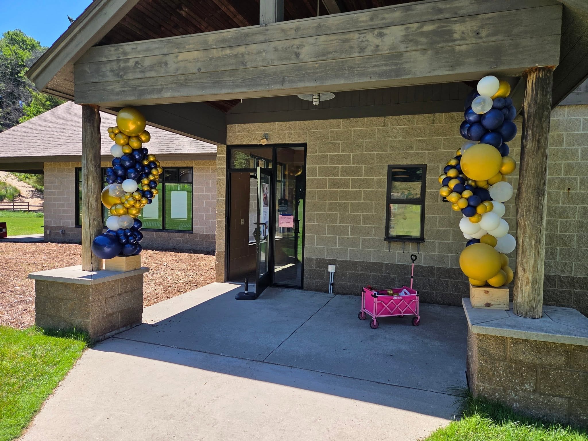 Navy and gold balloon columns flanking outdoor venue entrance