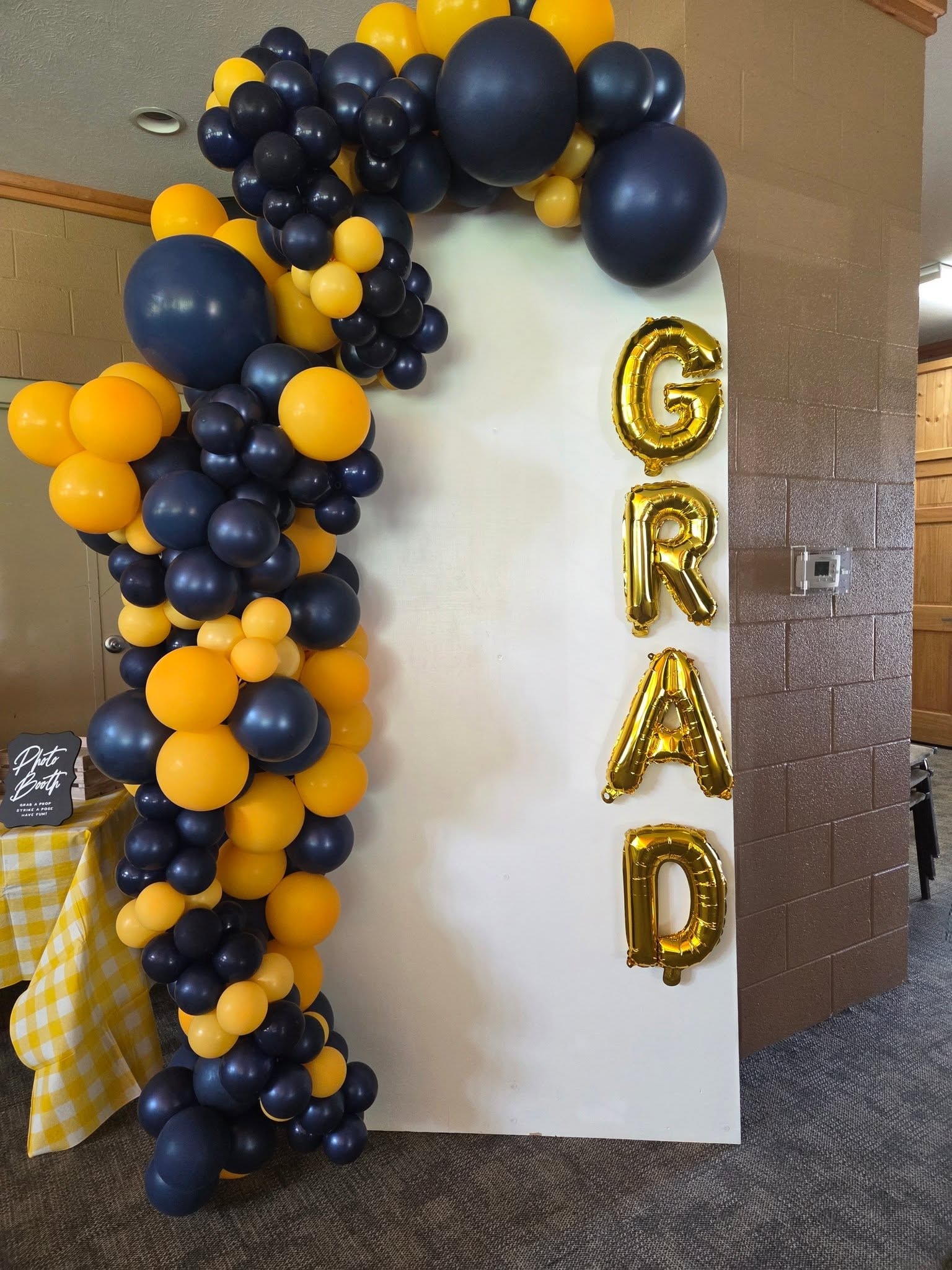 Navy and gold balloon garland with GRAD letter balloons on photo booth panel