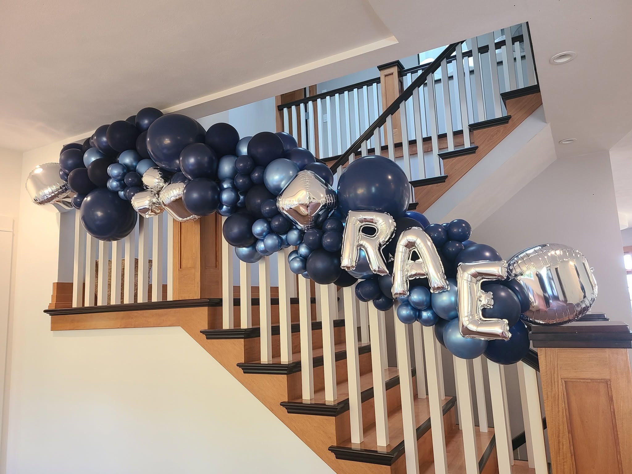 Navy and silver balloon garland on staircase railing with RAE letter balloons