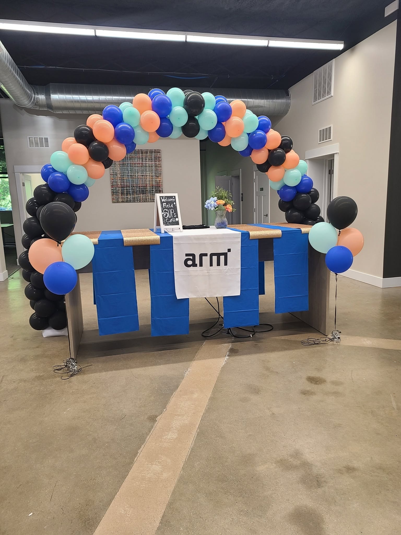 Corporate balloon arch in blue teal and black over branded table