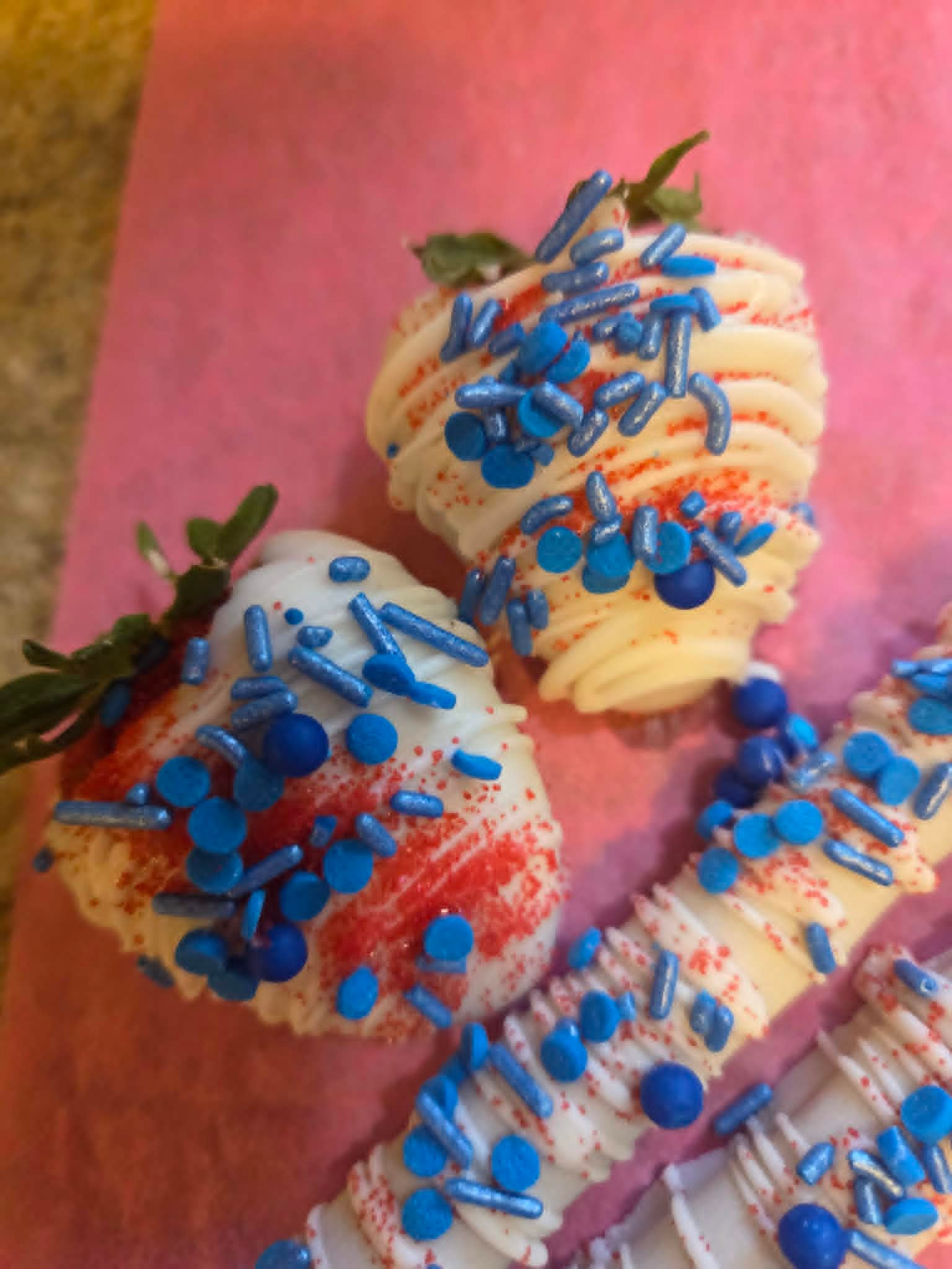 White chocolate strawberries with blue sprinkles and red sugar dust