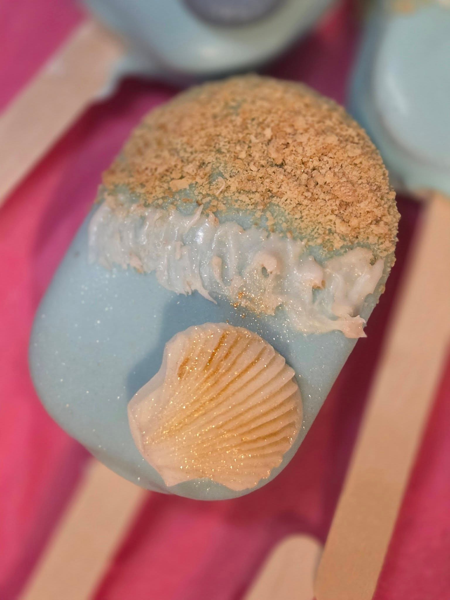 Blue beach cakesicle with seashell topper and graham cracker sand