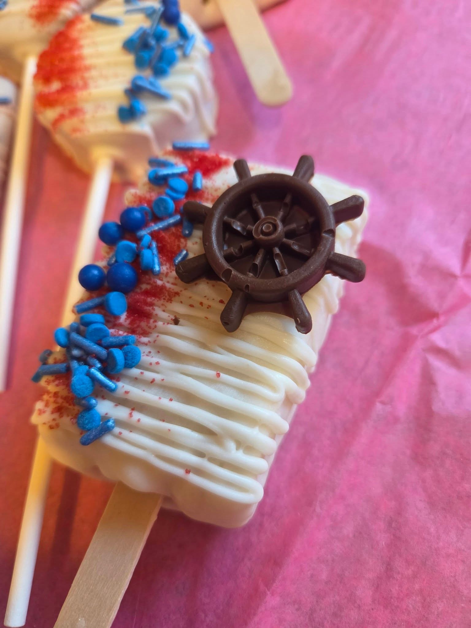 Nautical cakesicle with ship wheel topper and blue sprinkles